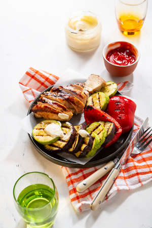 Grilled meat and vegetables with sauce on light table, healthy food close upの写真素材