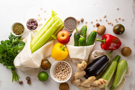 White table with healthy food in cotton shopping bagの写真素材