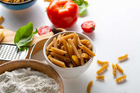 Whole wheat penne in small bowl and flourの写真素材