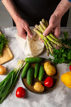 Men taking out fresh organic asparagus from cotton shopping bagの写真素材