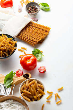 Different whole grain pasta and ingredients on tableの写真素材