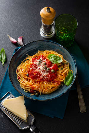 Spaghetti with red tomato sauce and cheese on black tableの写真素材