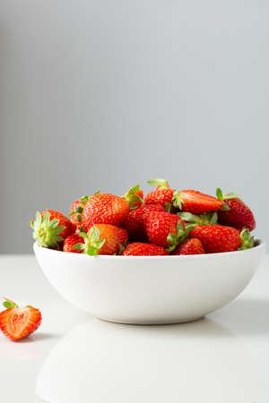 Fresh summer strawberry in white bowl on white tableの写真素材