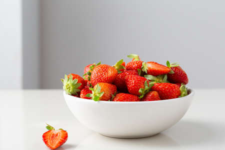 Fresh organic strawberry in white bowl on white tableの写真素材