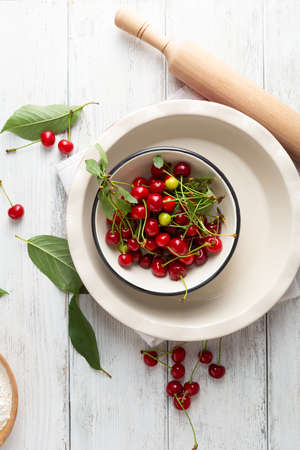 Pie dish and fresh cherry on white wooden surfaceの写真素材