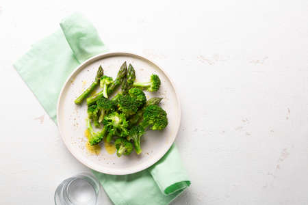 Overhead view of steames broccoli and asparagus on white surface