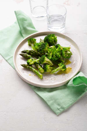 Close up of steames broccoli and asparagus on white surfaceの写真素材