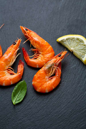Overhead view of Cooked tiger prawns with lime on black surfaceの写真素材