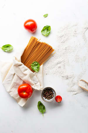 Whole grain spaghetti and flour on light surfaceの写真素材