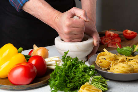 Hands Making sauce for pasta, fresh ingredients on white tableの写真素材