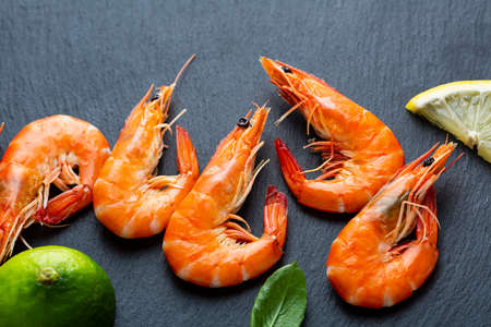 Close up of Cooked tiger prawns with lime on black surfaceの写真素材
