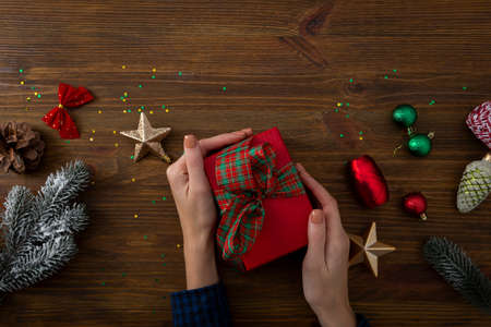 box in hands and Christmas decorations on wooden surfaceの写真素材