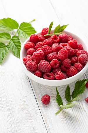 Close up of raspberry in bowl on white wooden tableの写真素材