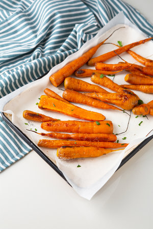 Roast carrots on baking tray and kitchen textileの写真素材