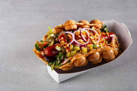 Street food waffle with sausage and salad on paper plateの写真素材