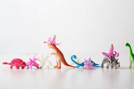 dinosaur toy and spring flowers on white stone backgroundの写真素材