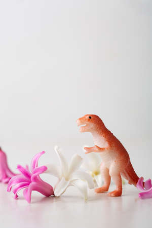 Toy dinosaur and white spring flowerの写真素材
