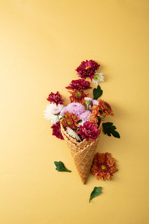 Overhead view of autumn flowers in waffer cone on golden backgroundの写真素材