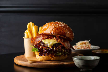 Close up of meat hamburger with cheese and bacon on black tableの写真素材