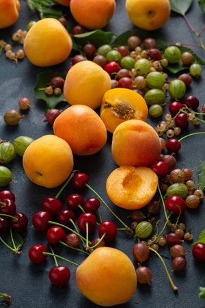Fresh apricots and cherries on dark surface, summer fruits foodの写真素材
