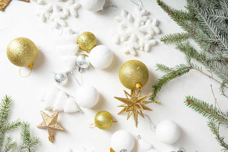 Overhead view of golden and white Christmas decorations on light surface green eve branchesの写真素材