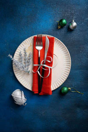 Christmas table detail plate with decorations top view on dark blue surface