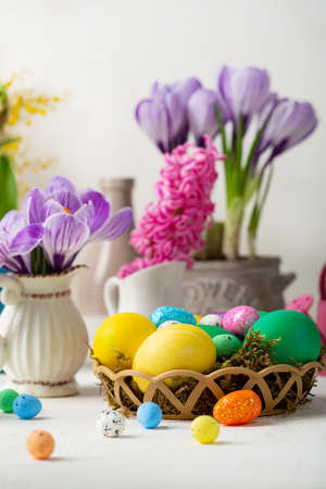Flowers crocus and Easter eggs green and yellow on light tableの写真素材
