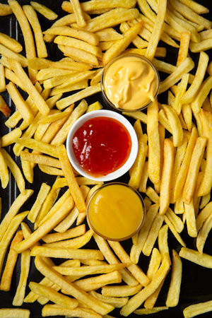 From above of appetizing golden fried potatoes with three dips