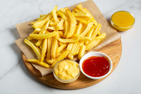French fries with set sauces on wooden board junk foodの写真素材