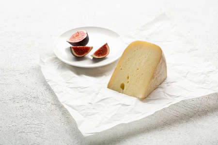 One cheese piece on wrapping paper and figs fruits foodの写真素材