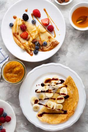 Two Crepes with banana slice, berries jam and chocolate sauce food overhead viewの写真素材