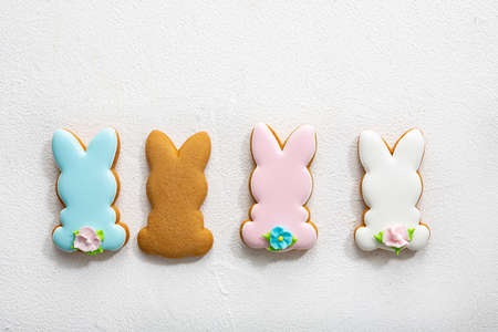 Overhead view of four Easter bunny cookies on light surface spring holiday