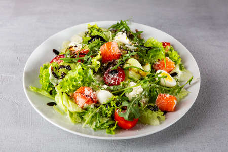 Close up of fresh salad with salmon slices and cheese on white plateの写真素材
