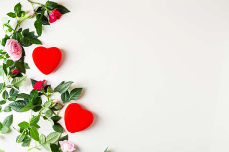Overhead view of small garden roses and red hearts on light surface copy spaceの写真素材