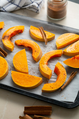 Sliced pumpkin with cinnamon on baking sheet cooking foodの写真素材