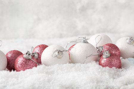 White and pink Christmas tree decorations on snow festive backgroundの写真素材
