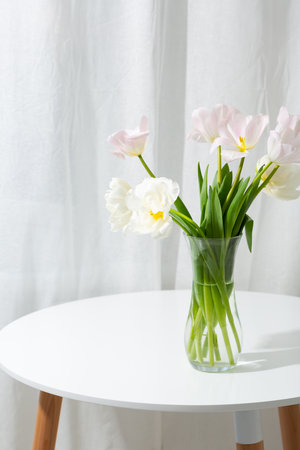 Light spring flowers in vase on white tableの写真素材