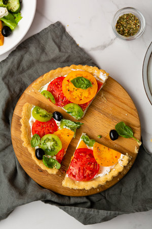 Top view of ssliced pie with cheese and tomatoes olive quiche on textile healthy foodの写真素材