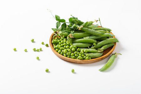 Close up of ripe green sweet peas pods and beans on plate light surfaceの写真素材
