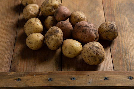 Close up of raw potatoes root on wooden board food harvest conceptの写真素材