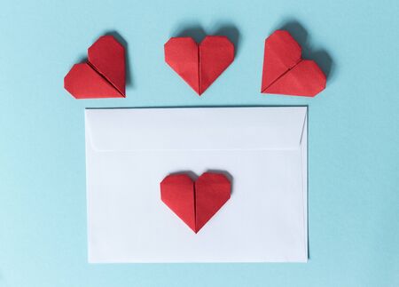 White paper envelope and red origami hearts on a blue background. View from above.の写真素材