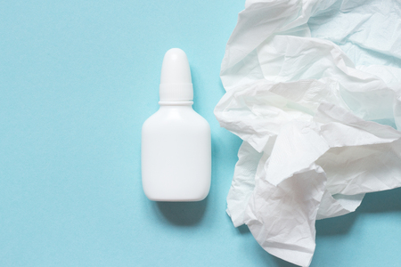 Crumpled paper napkin and nasal drops on blue background. Mock up. Concept flu, colds, runny noseの写真素材