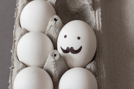 Egg with mustaches and eyes. Carton of raw white chicken eggs.