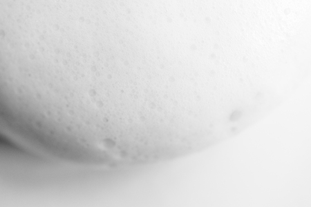 White smooth foam soap form abstract background with selective focus. Close up, macro