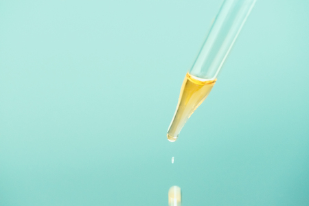 Glass dropper with oil serum and drop close upの写真素材
