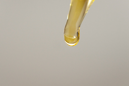 Pipette with golden cosmetic oil drop close upの写真素材
