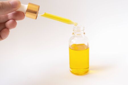 Dropper with oil serum glass bottle and female hand on white backgroundの写真素材
