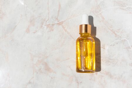 Oily serum in glass bottle with pipette on marble background with copy space. Luxury cosmeticの写真素材
