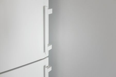 Close-up white refrigerator door and gray wall with copy space