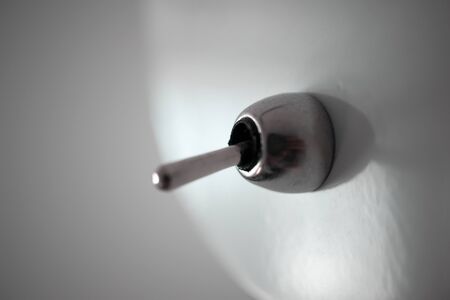 Close-up switch on metal white electric lamp on gray wallの写真素材
